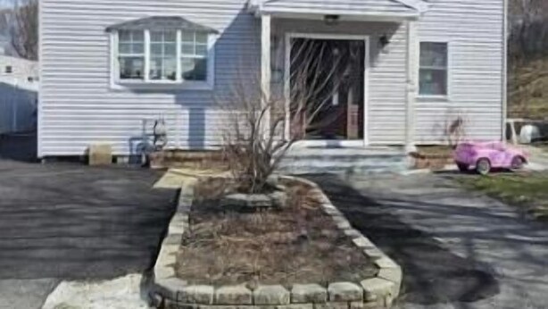 A two-story house with a front porch, a driveway, and a small garden area. - Charming B&B with AC, WiFi in Phenomenal Revere (Revere)