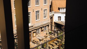 Blick auf einen Innenhof mit Gebäuden, einer Treppe und Außenbestuhlung.
