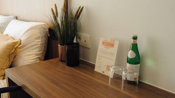 Una mesa de madera con un letrero de bienvenida, una botella verde y dos vasos.