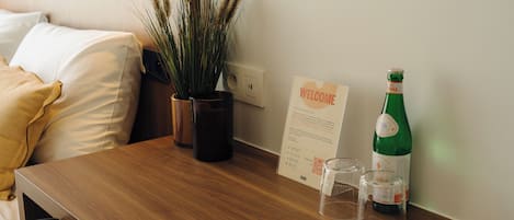 Una mesa de madera con un letrero de bienvenida, una botella verde y dos vasos.