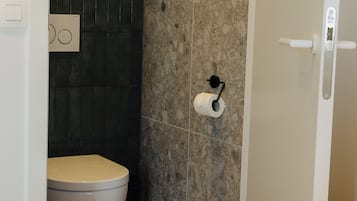 Casa de banho com sanita, suporte para toalhas e zona de duche.
