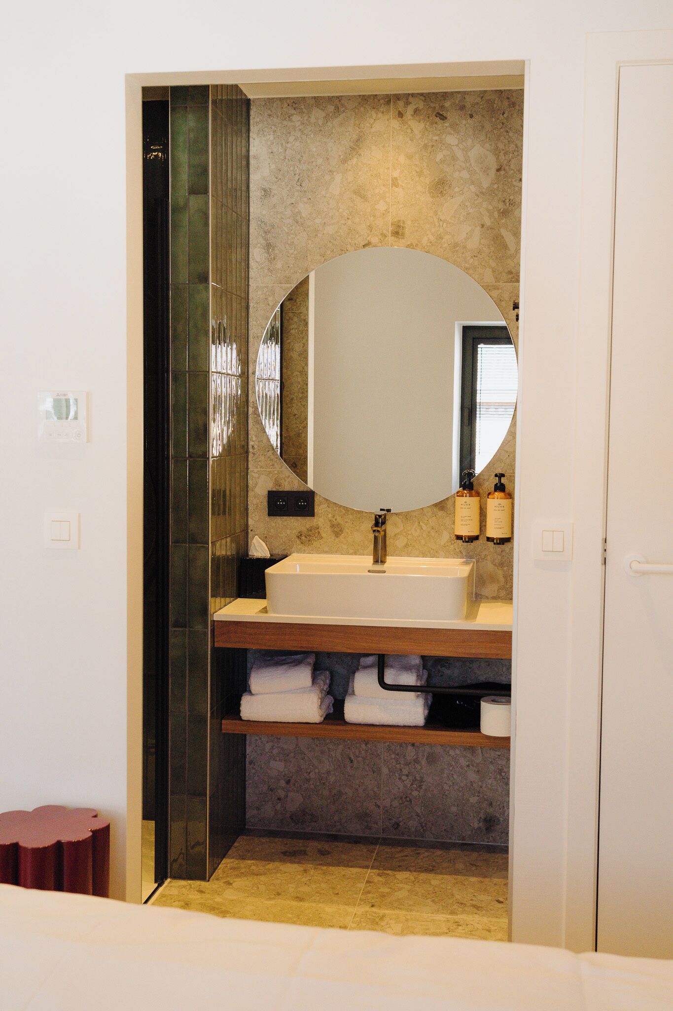 A bathroom with a large mirror, a sink, and a towel rack.
