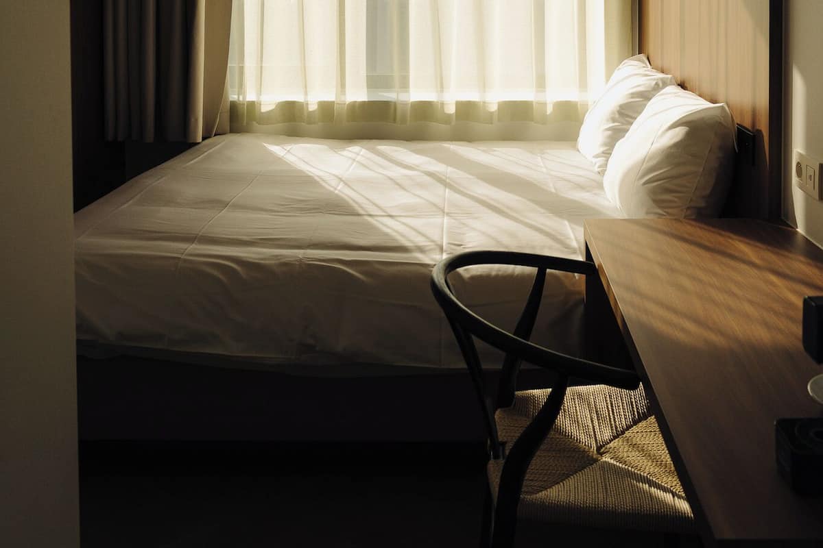 A bedroom with a bed, a desk, and a chair.