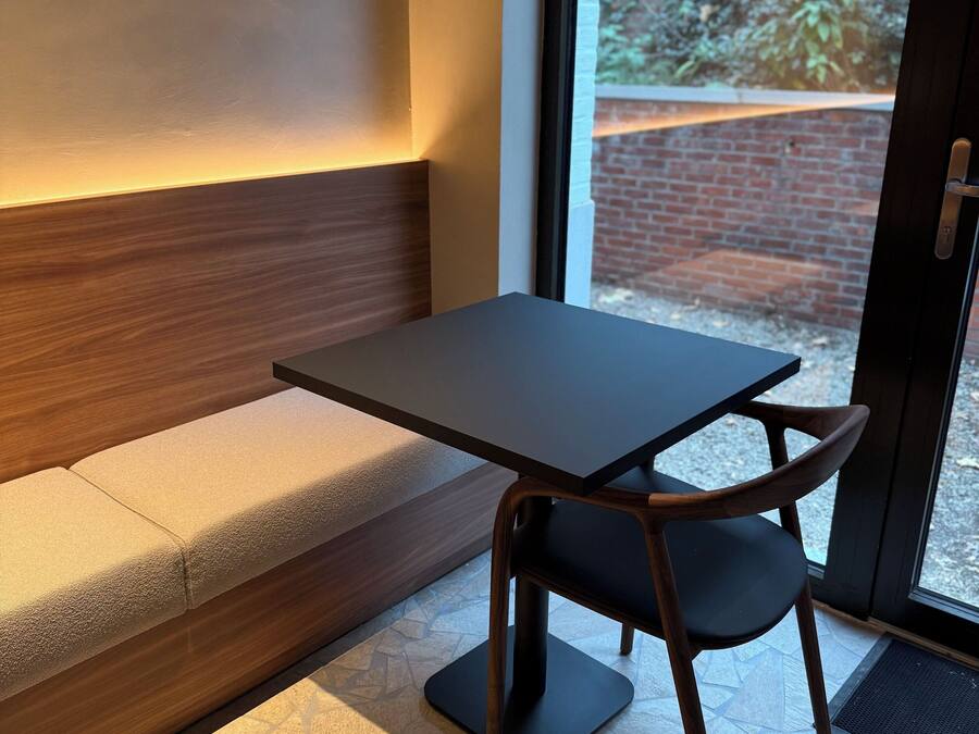 A modern interior with a dark wooden table and a cushioned bench.