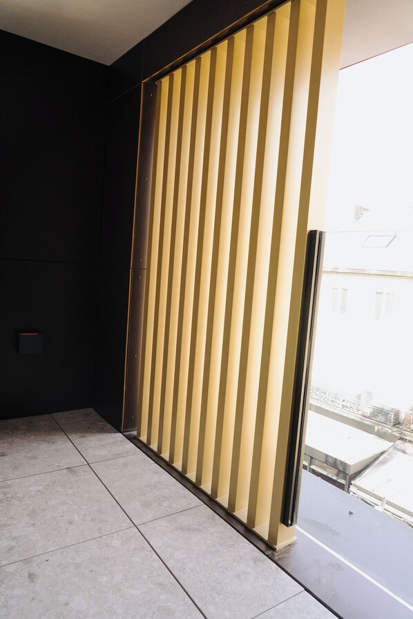 A room with a sliding door, a tiled floor, and a view of buildings outside. - Door9 (Hasselt)
