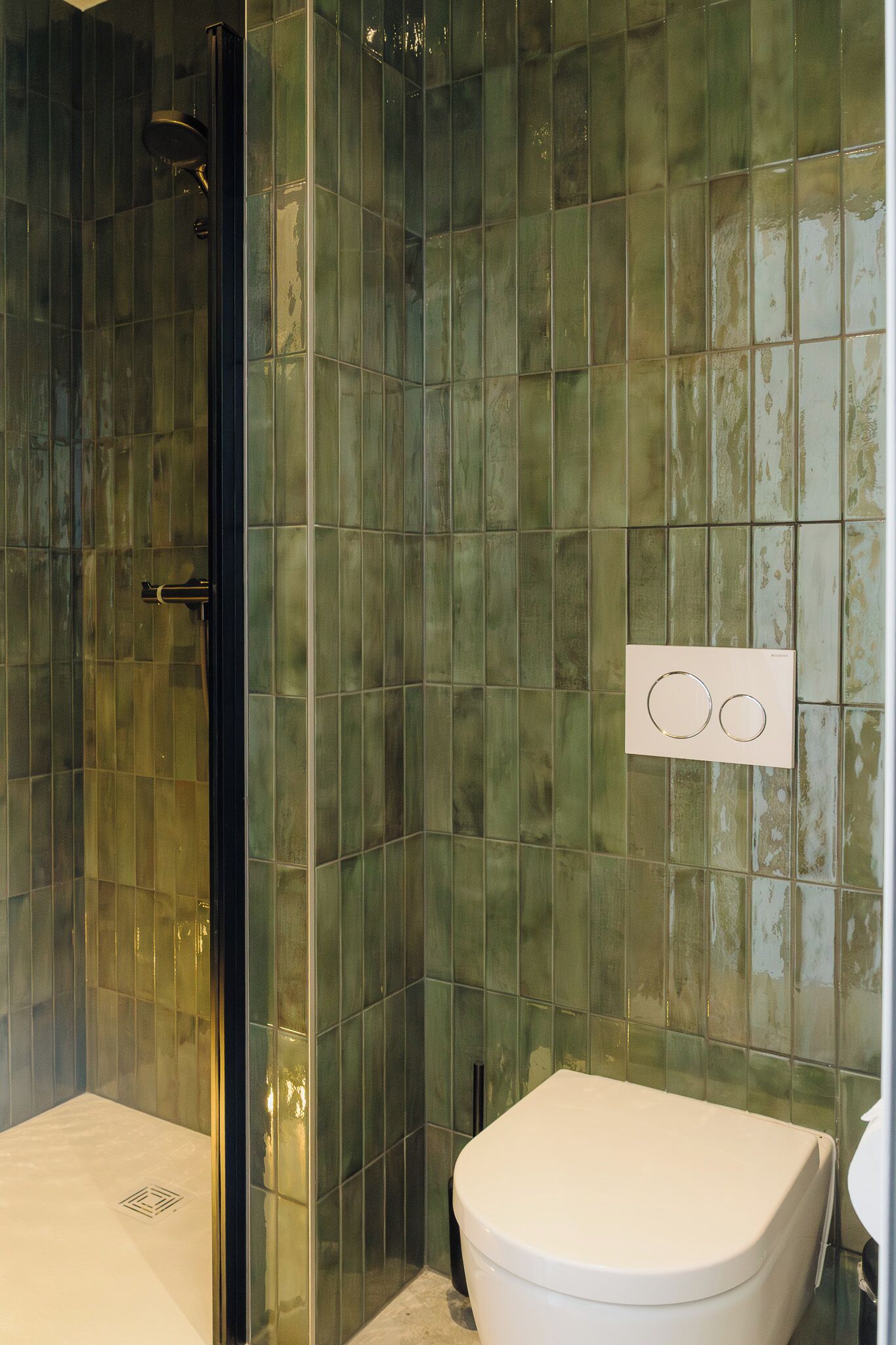 A bathroom with a glass shower enclosure, a white toilet, and a tiled wall.