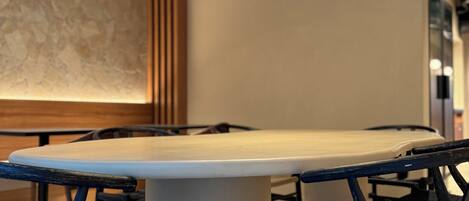 A conference room with a large oval table, black chairs, and a modern pendant light fixture.