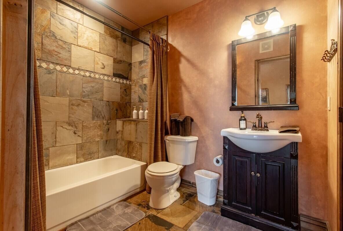 Une salle de bain comprenant une baignoire, des toilettes, un meuble-lavabo et un espace douche avec un mur carrelé.