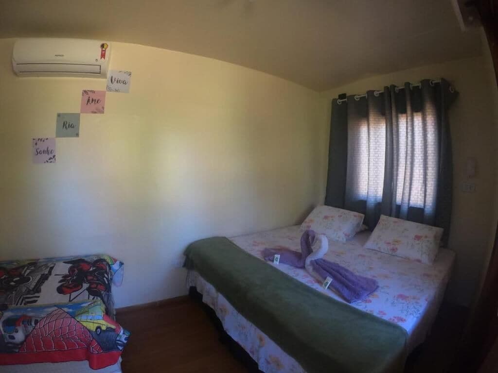 Un dormitorio con una cama, una mesita, aire acondicionado y una ventana con cortinas.