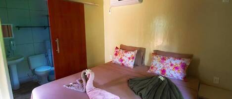 A hotel room with a bed, a bathroom, and an air conditioning unit on the wall.