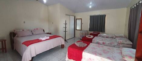 A hotel room with two beds, a small table, a mirror, and a door.