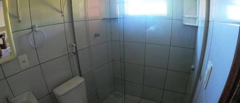 Un baño pequeño con inodoro, lavamanos y ducha.