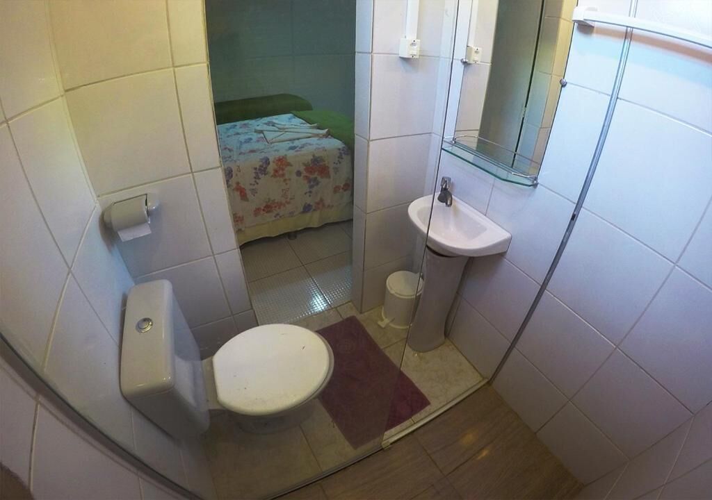 Een kleine badkamer met toilet, wastafel en een douchecabine van glas.