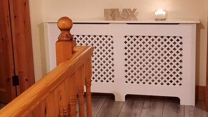 A wooden staircase leading to a room with a white console table, a round mirror, and a 'RELAX' sign. - House on the Lane, in the tranquil Village of Cong, Ireland. (MO)