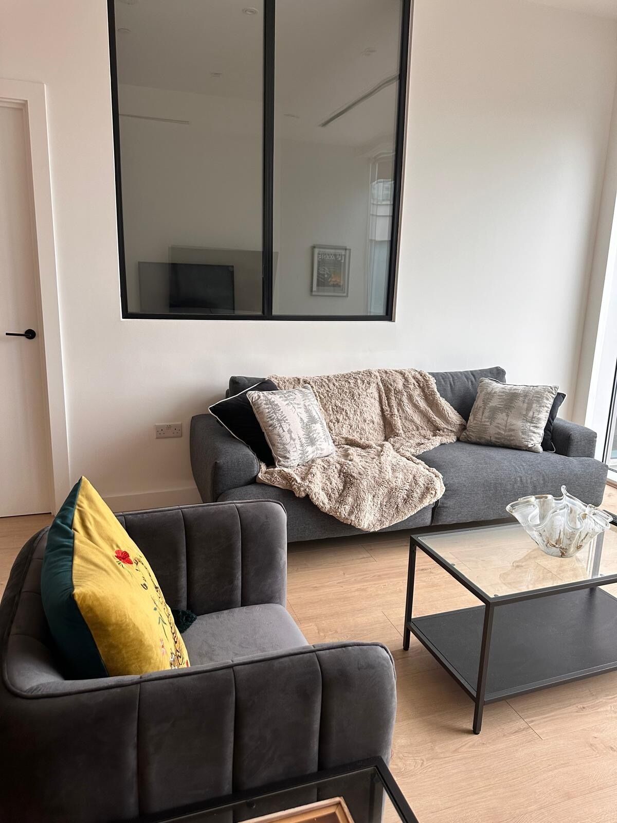 A modern living room with two sofas, a coffee table, and a large window.
