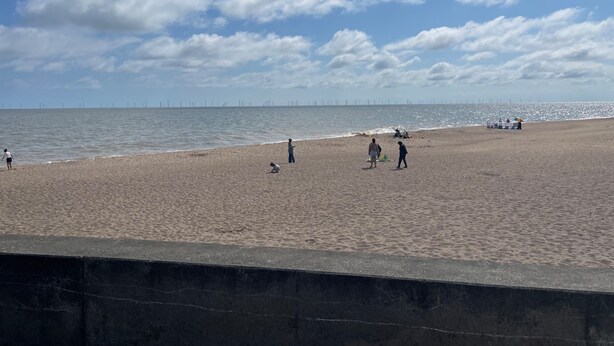 Ein Strand mit blauem Himmel und einigen Personen.