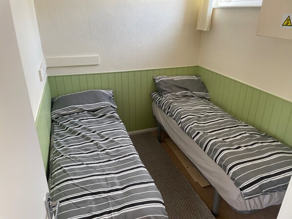 Un alojamiento pequeño, de una sola habitación, con dos camas individuales, cada una con ropa de cama a rayas.