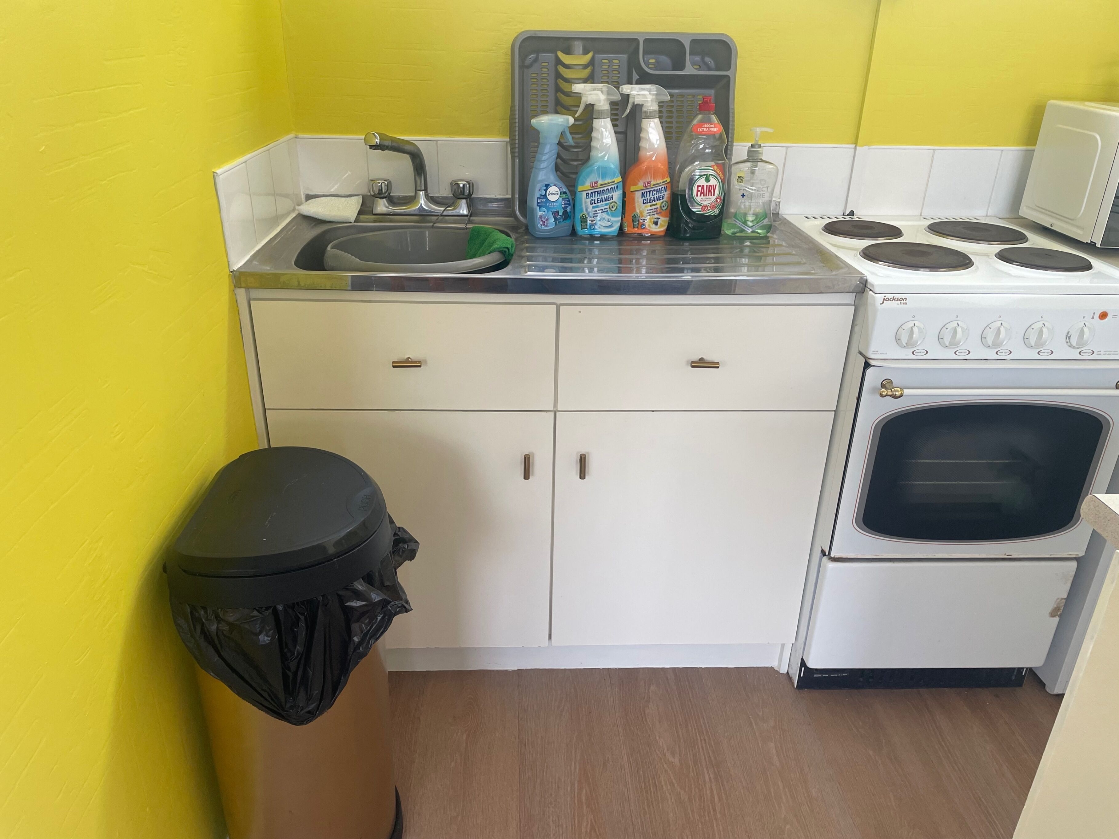 A compact kitchen with a sink, stove, and cabinets.
