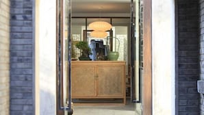 A doorway leading to a room with a large mirror, a wooden cabinet, and a hanging lamp.