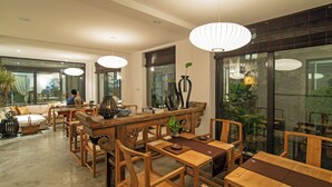 A spacious dining area with wooden furniture and pendant lighting. - Beijing 161 Lezai Nanluo Hotel (Beijing)