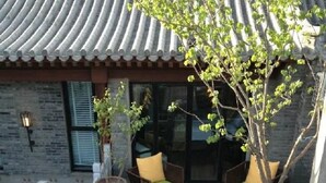 A traditional Korean-style outdoor seating area with a wooden table and wicker chairs with green cushions. - Beijing 161 Lezai Nanluo Hotel (Beijing)