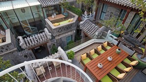 A traditional-style courtyard with a wooden dining table, cushioned seating, and a spiral staircase. - Beijing 161 Lezai Nanluo Hotel (Beijing)