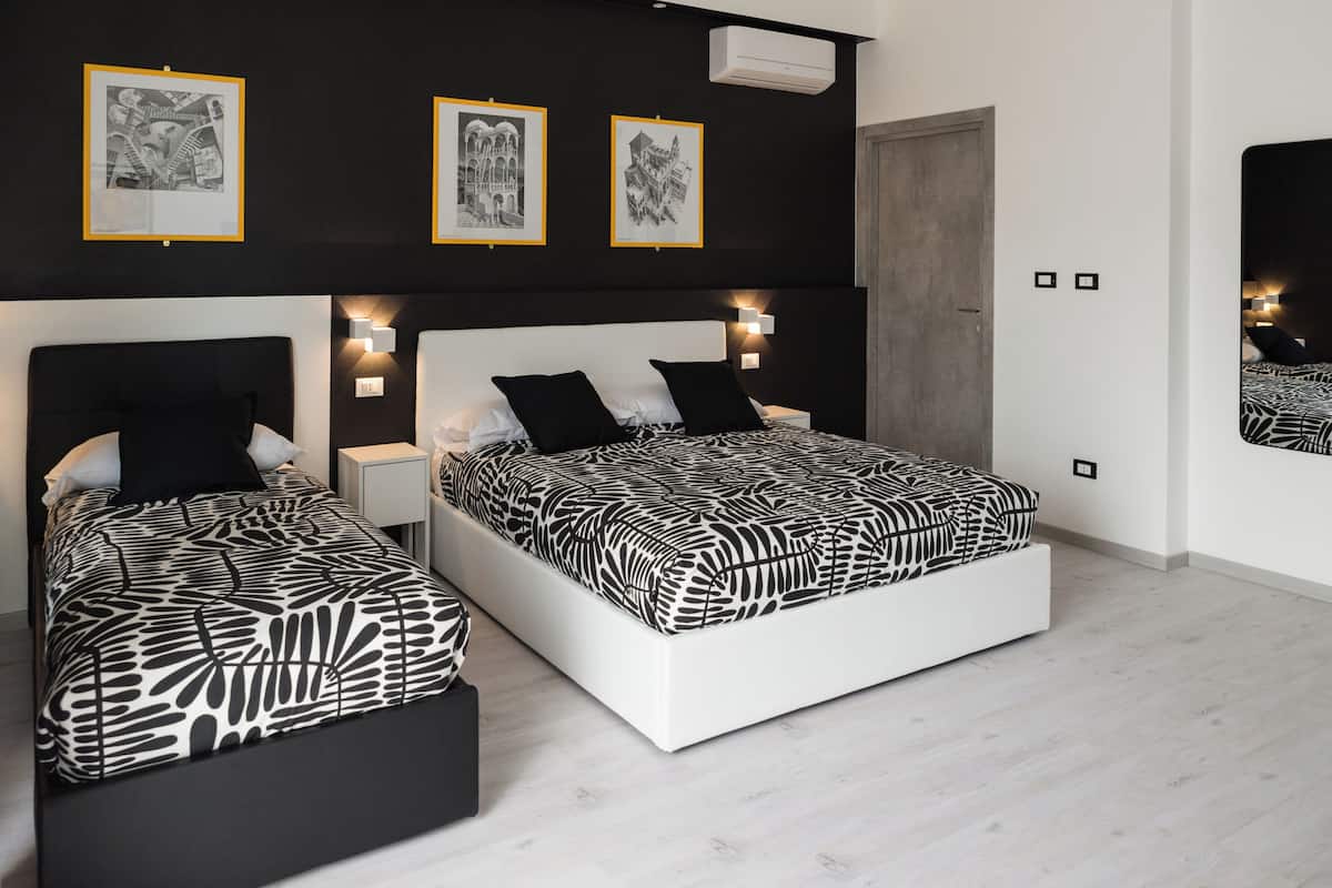 Una camera da letto moderna con due letti, biancheria a letto a motivi bianchi e neri e opere d'arte incorniciate al muro.