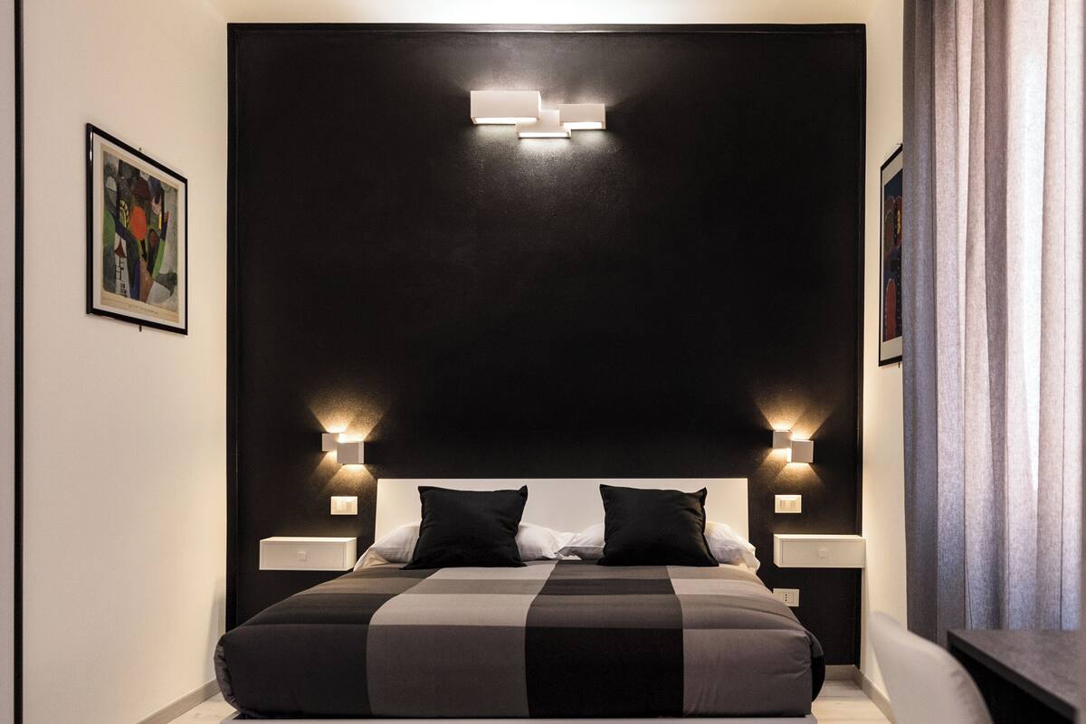 Una camera da letto moderna con un letto grande, lampade sui comodini e una testiera con illuminazione integrata.