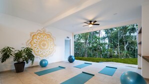 Una sala de yoga con colchonetas, pelotas de ejercicio y un gran mural en la pared.