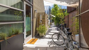 A narrow outdoor corridor with a bicycle rack, potted plants, and a wooden fence.