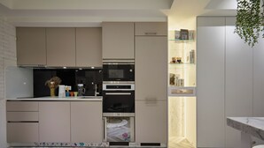 Une cuisine moderne dotée d’appareils électroménagers intégrés, d’un parquet à motifs en chevrons et d’un meuble vitré.