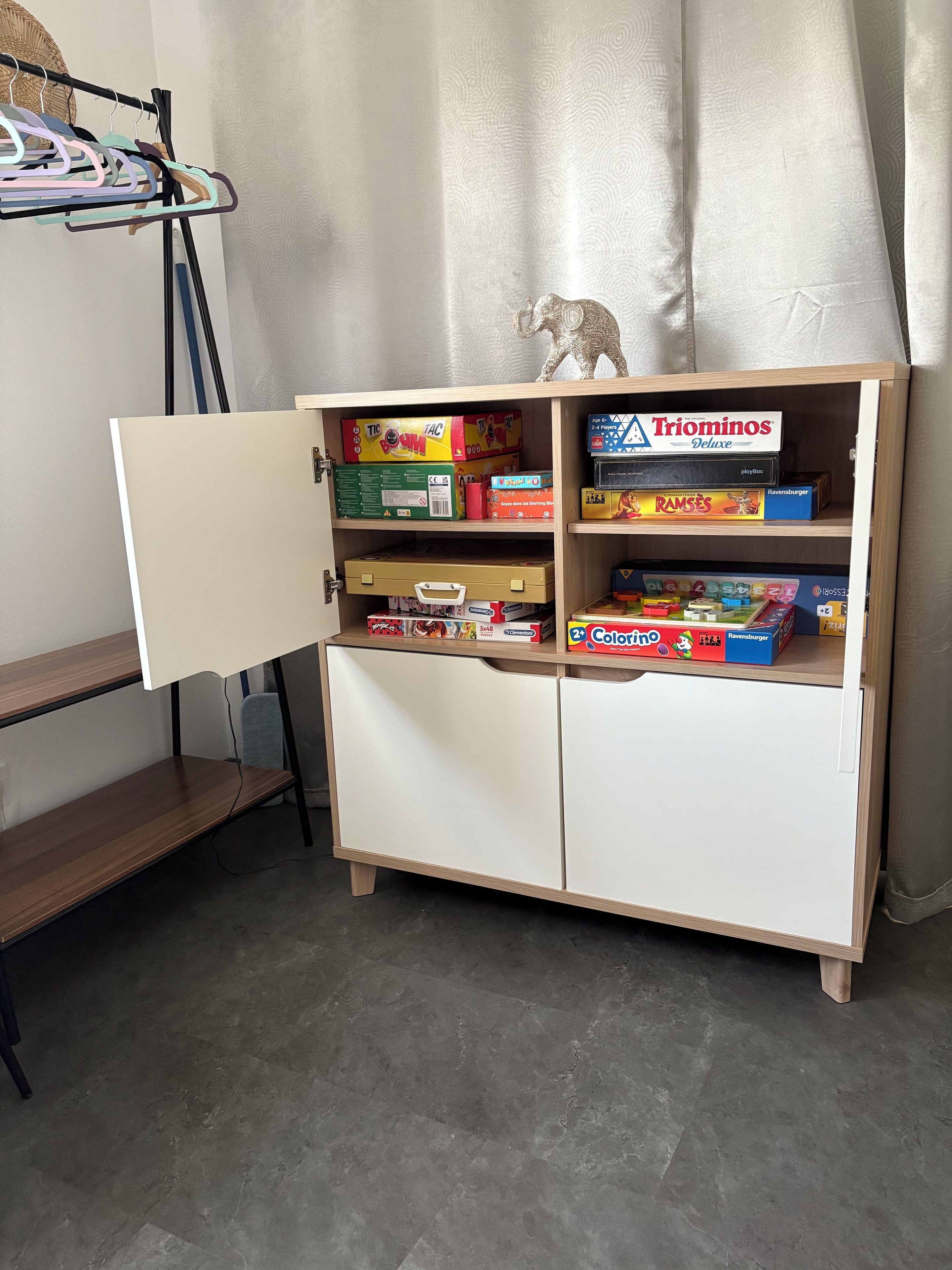 Un meuble en bois aux portes ouvertes, où sont exposés différents jeux de société.