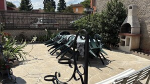 Zona de pati amb mobiliari exterior, una paret de pedra i una petita construcció de pedra.