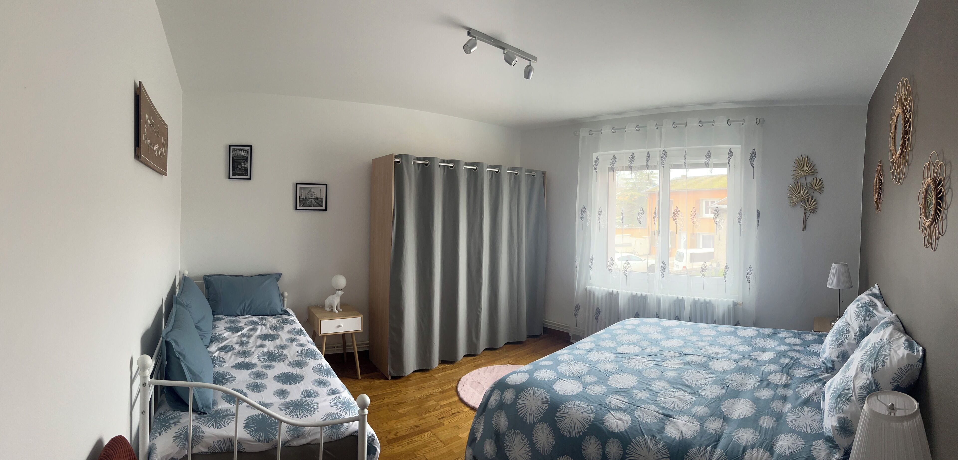 Ein Schlafzimmer mit zwei Betten, einem Nachttisch, Vorhängen an einem Fenster und Wanddekorationen.