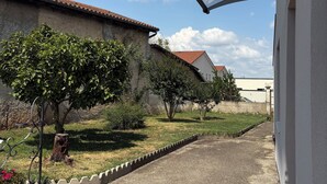 Un pati amb un camí de grava, una tanca metàl·lica i un edifici amb teulada d'aquarella.