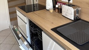Una cuina compacta amb taulell de fusta, forn integrat, torradora i cafetera.