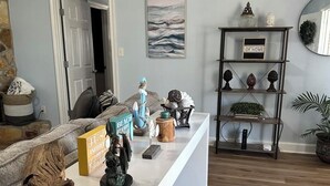 Una sala de estar con una consola blanca, una estantería y una puerta que da a otra habitación.