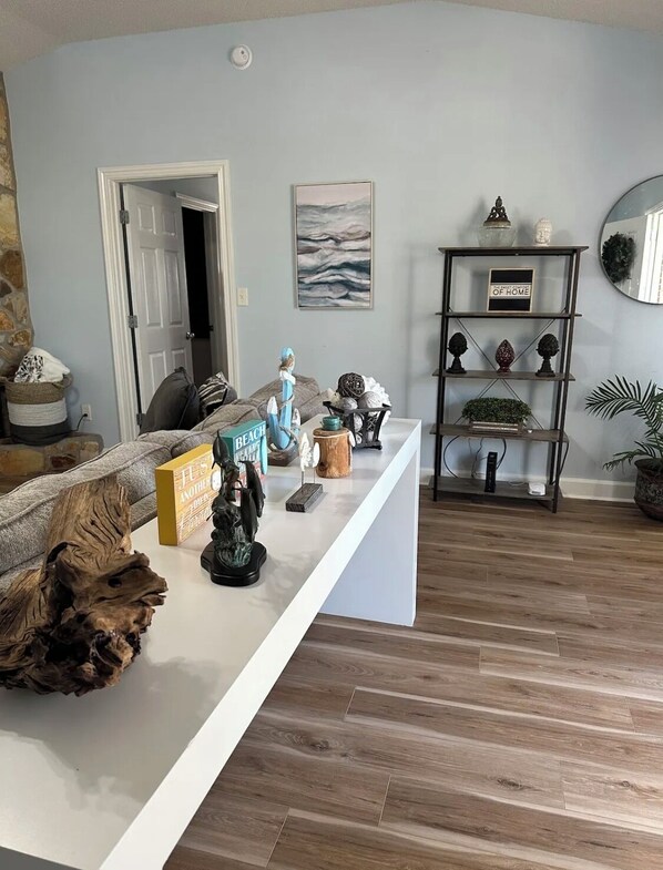 A living room with a white console table, a bookshelf, and a door leading to another room.