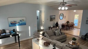 Una sala de estar moderna con un sofá modular, una mesa de centro y un comedor al fondo.
