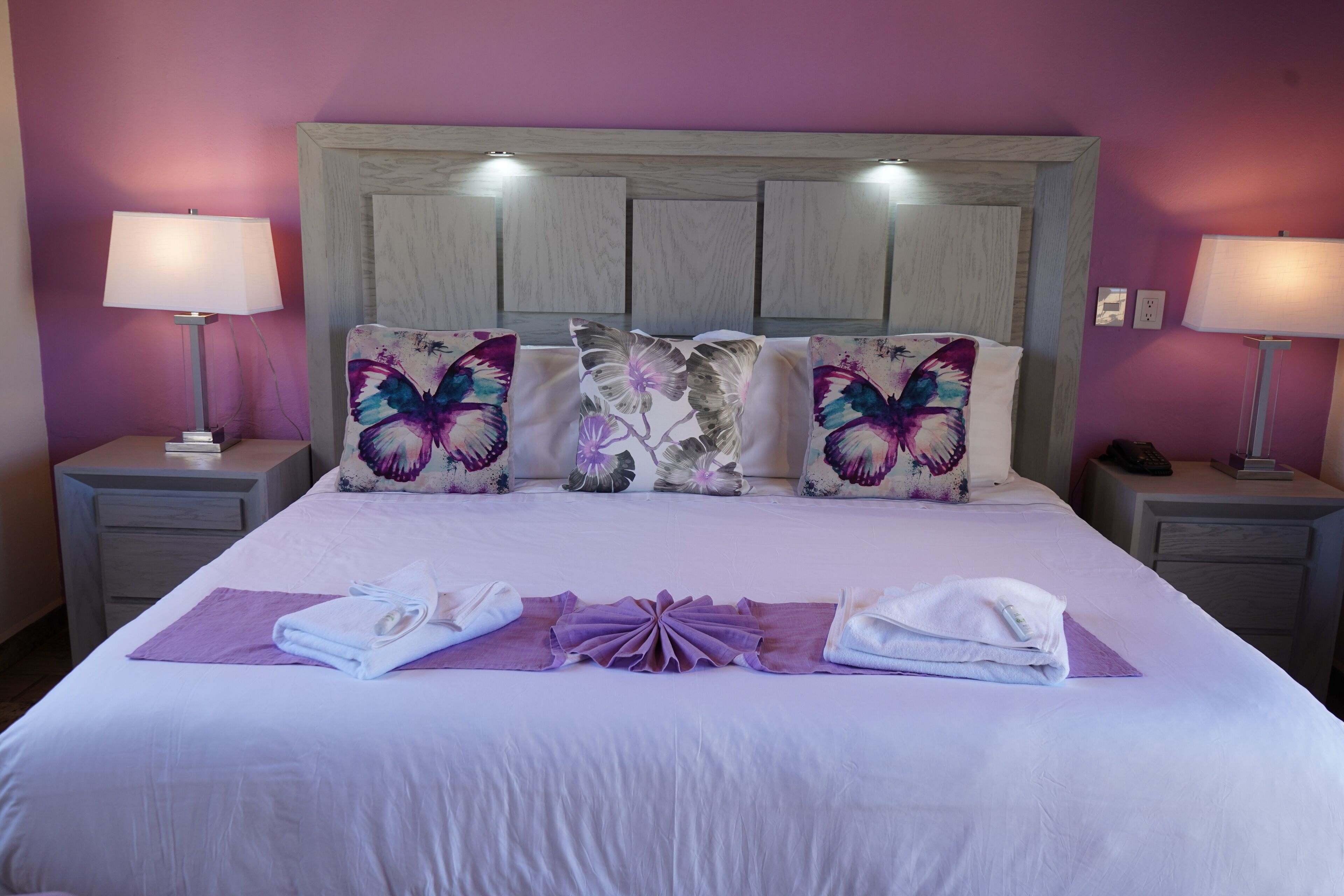 A neatly made bed with a headboard, two bedside lamps, and decorative pillows.