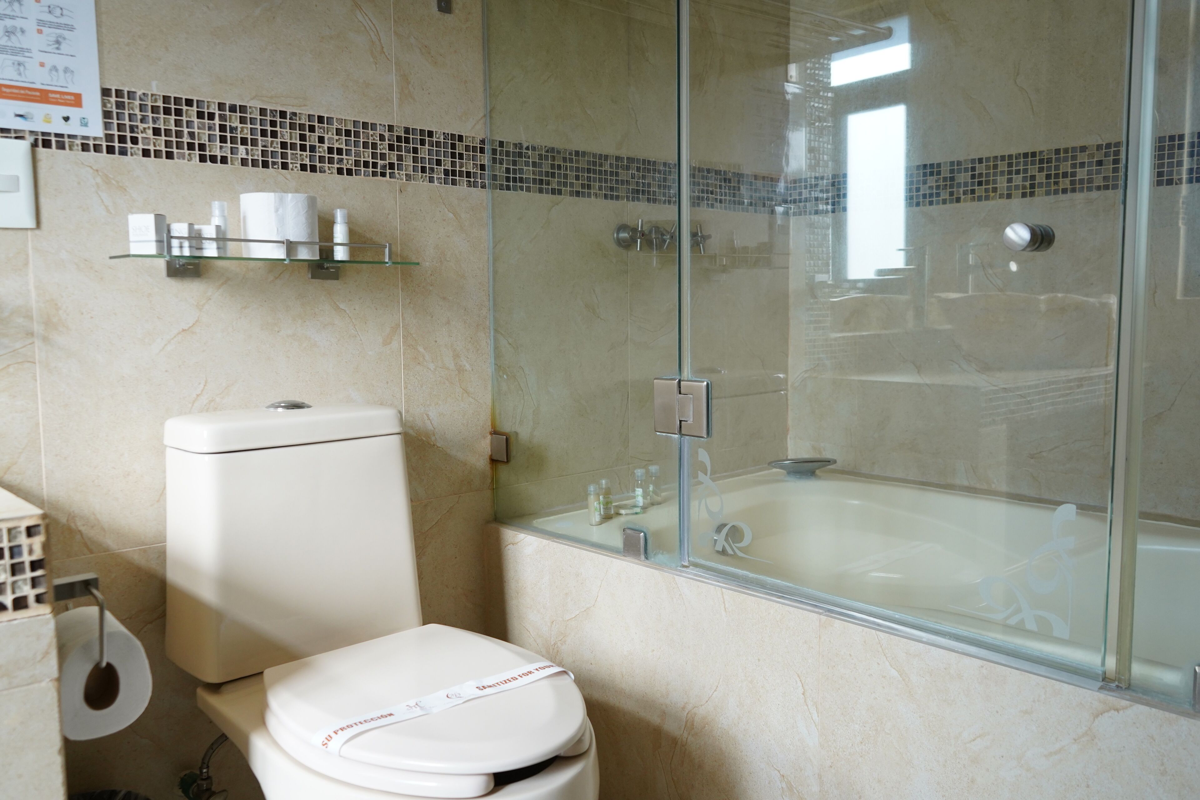 Un baño con inodoro, cabina de ducha de vidrio y bañera.