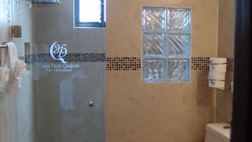 A bathroom with a shower, toilet, and a window.