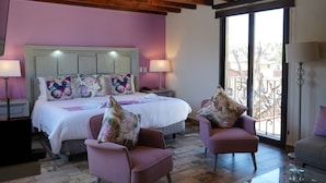 Une chambre à coucher avec un lit, deux chaises, une table de chevet et une fenêtre donnant sur un beau paysage.