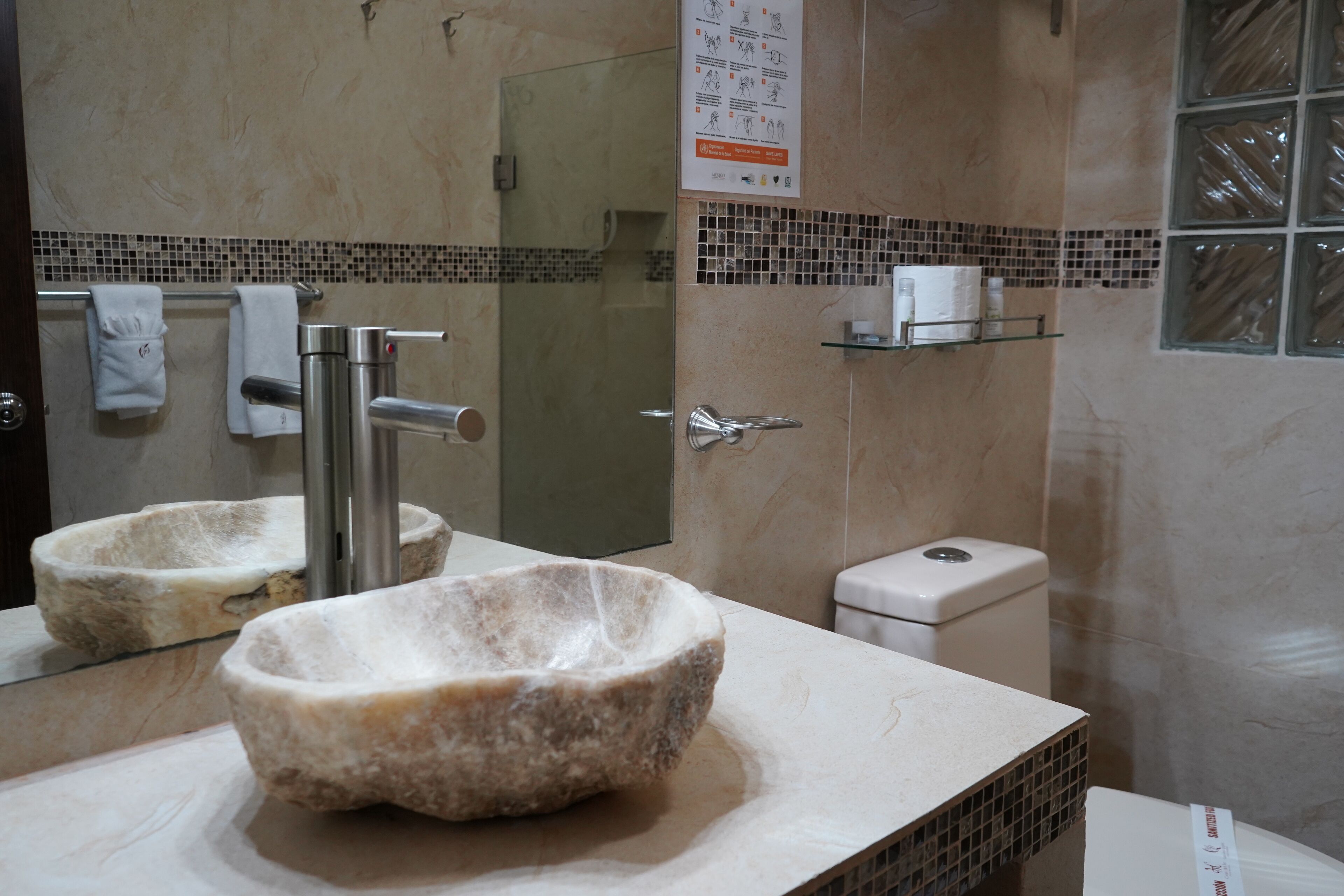 Une salle de bain avec un lavabo en pierre, des toilettes et un espace douche.