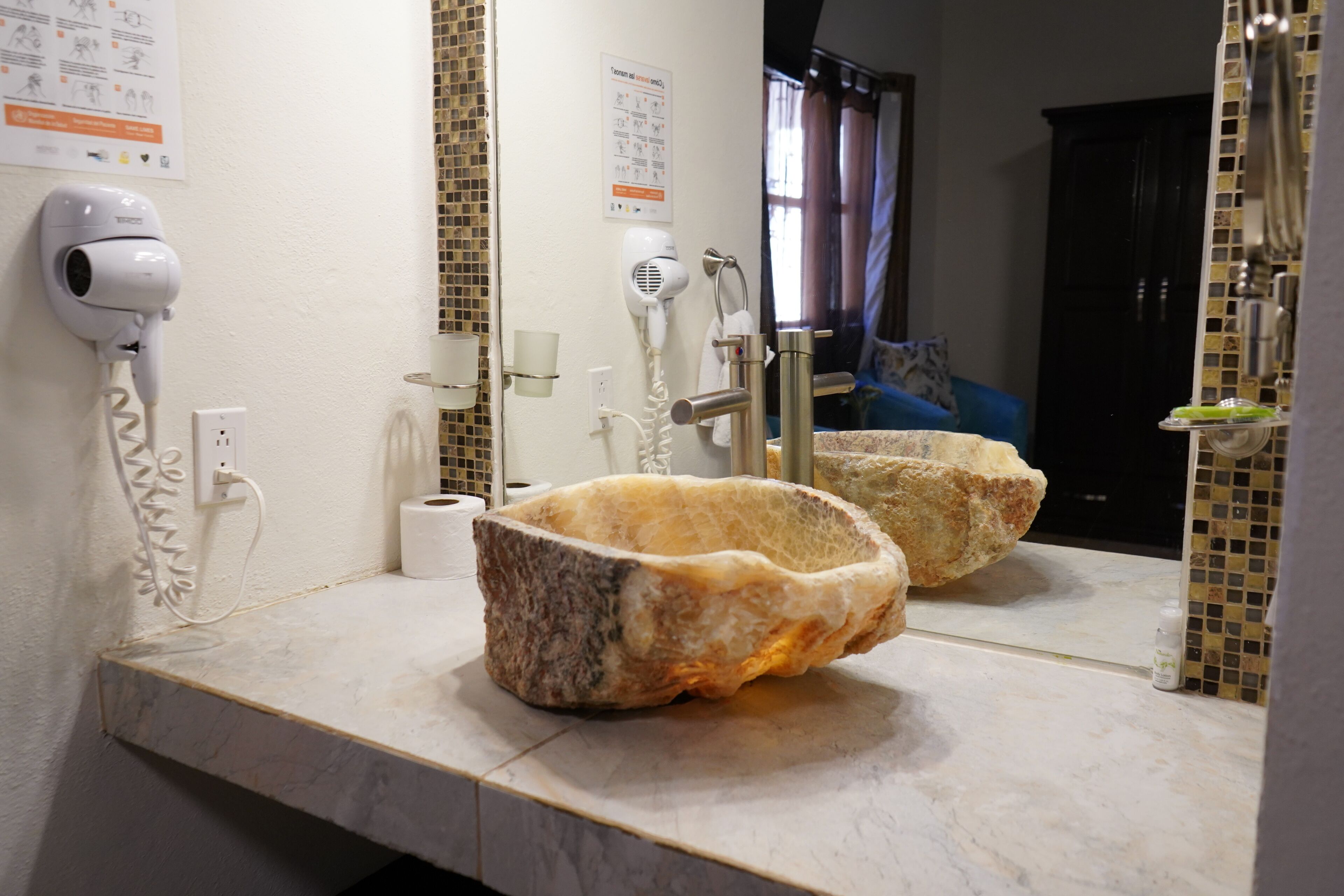 A bathroom with a marble sink, a hairdryer, and a towel rack.