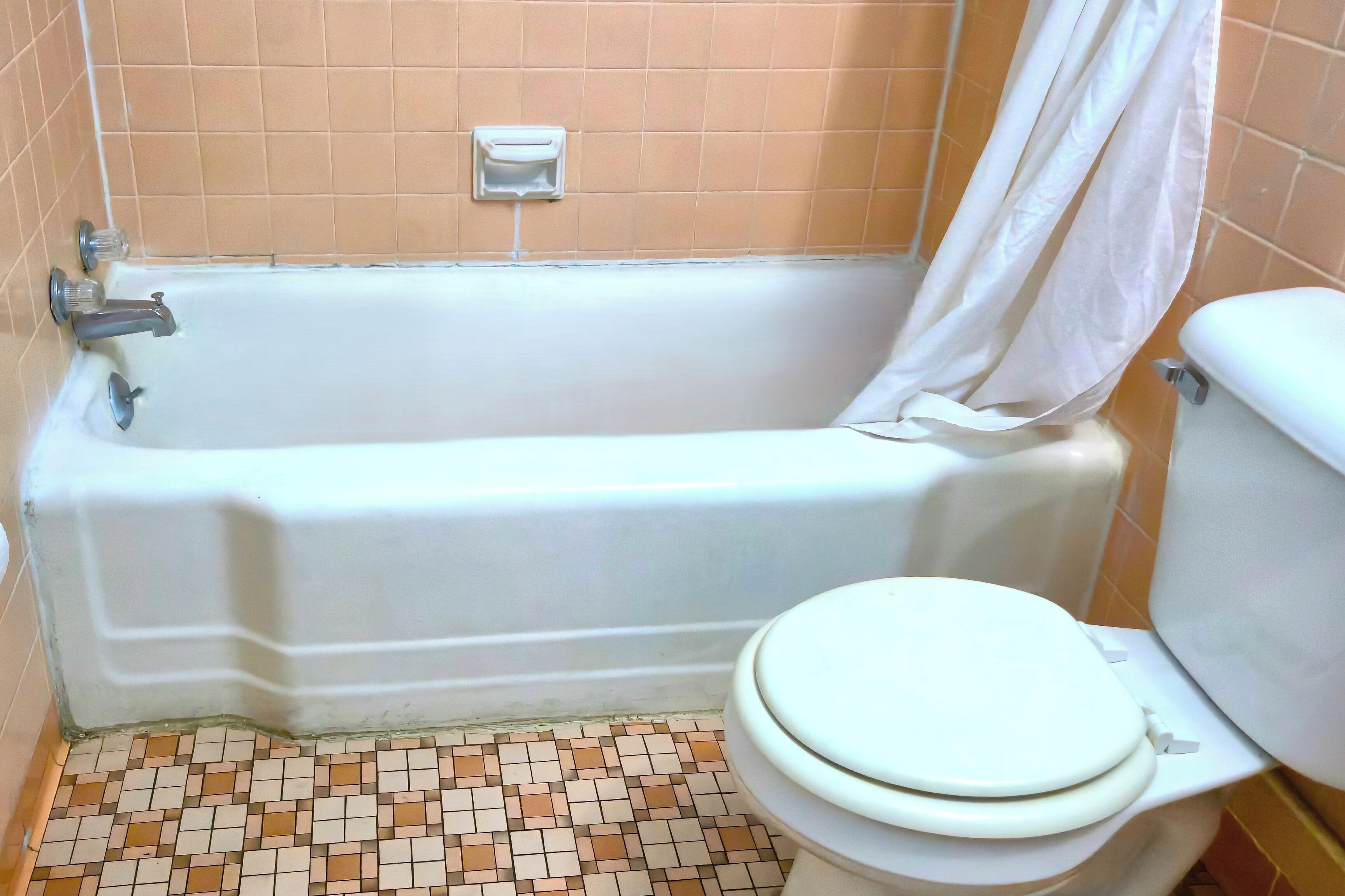 A bathroom with a bathtub, toilet, and a tiled floor.