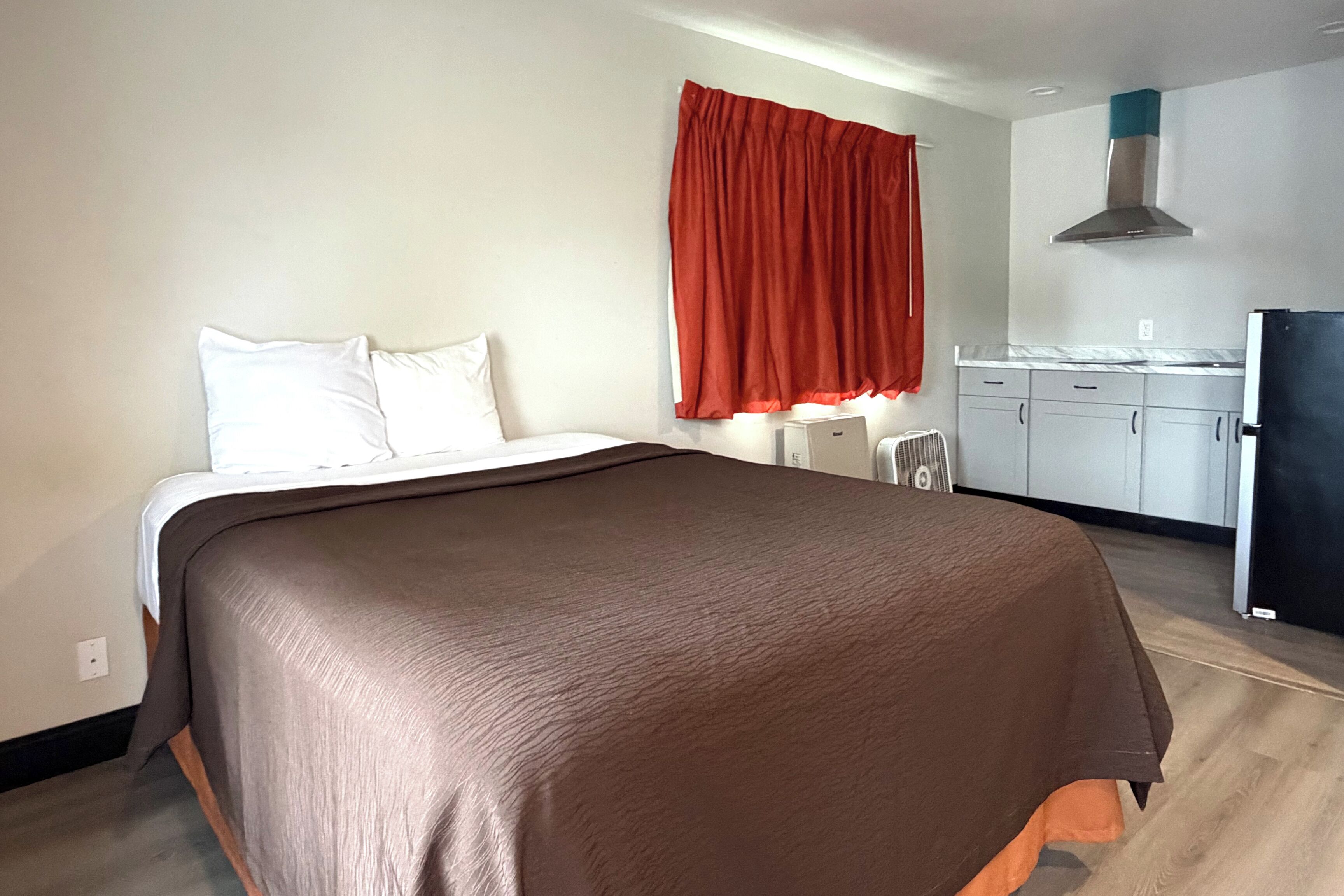 A hotel room with a bed, a desk, and a kitchenette.