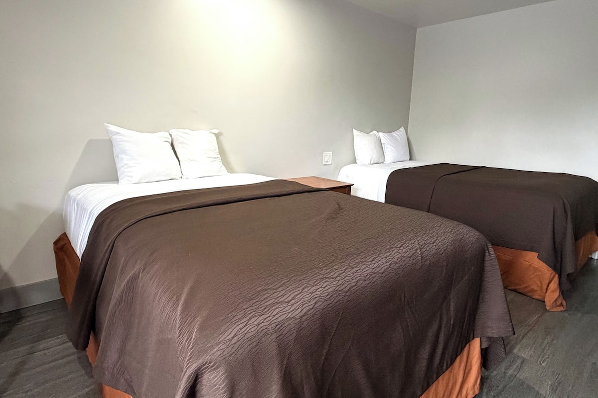 A hotel room with two beds, each with a brown bedspread and white pillows.