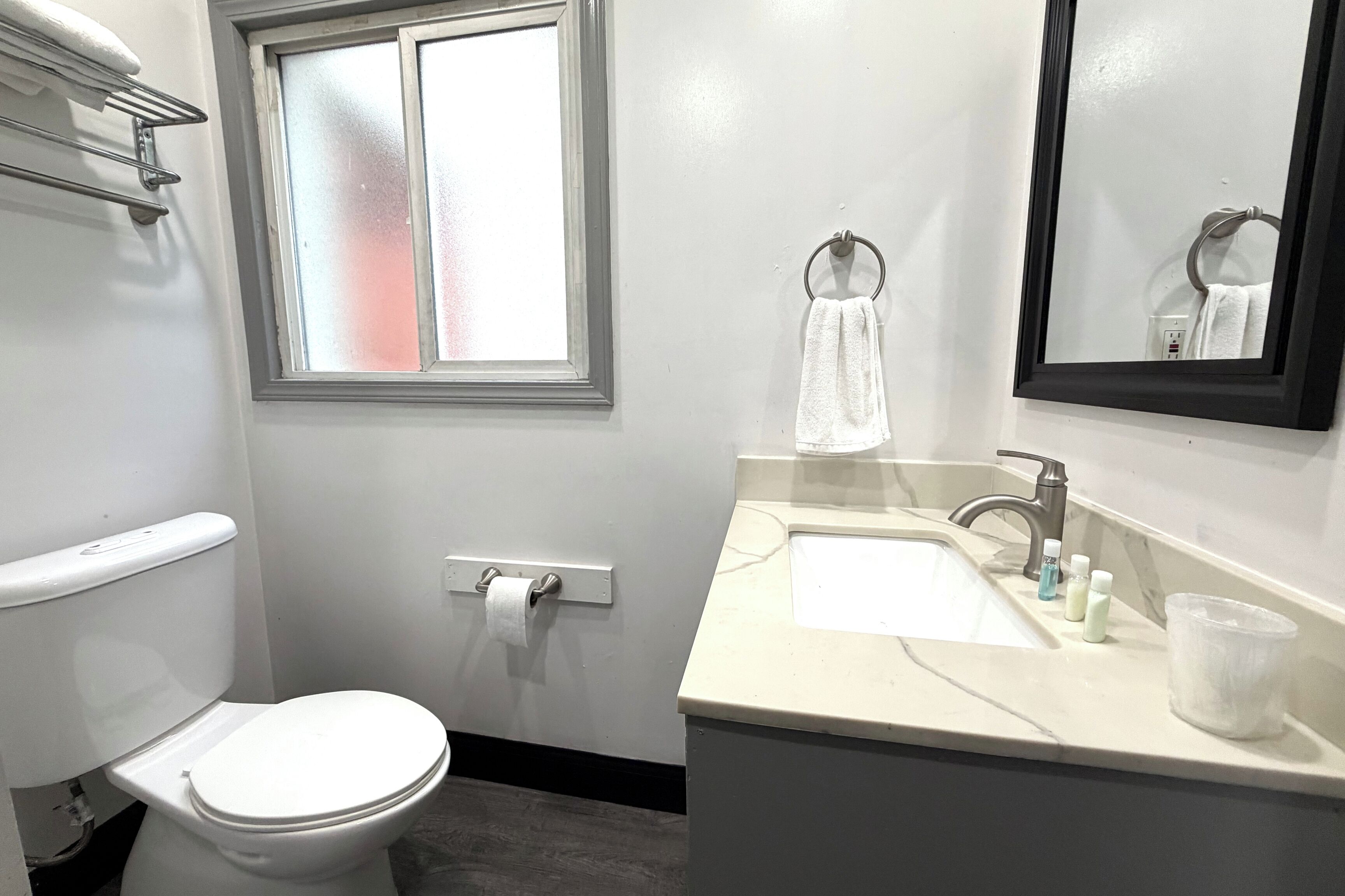 Un baño con inodoro, lavabo con espejo y ventana.