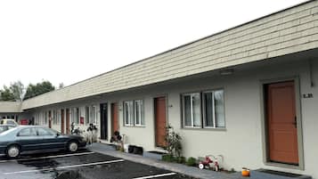 Un motel amb una filera d'habitacions, cadascuna amb una porta i una finestra. Hi ha un cotxe estacionat al davant, i una testuda i un petit cotxe de joguina vermell a la vorera.